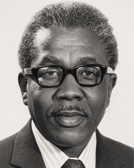 Black-and-white archival portrait of James Alexander wearing glasses and a suit
