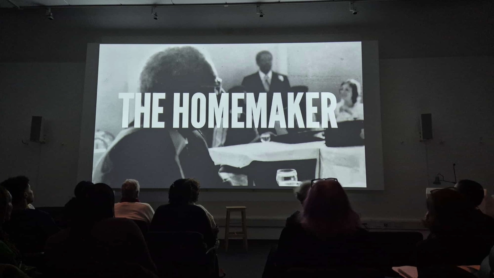 Audience seated in a screening room with The Homemaker projected on screen